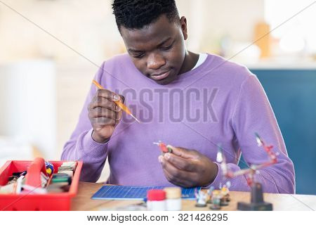 Teenage Boy Painting War Game Model Figures At Home