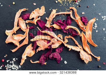 Healthy Homemade Vegetable Chips From Beetroot And Carrot With Salt And Origano On Black Background.