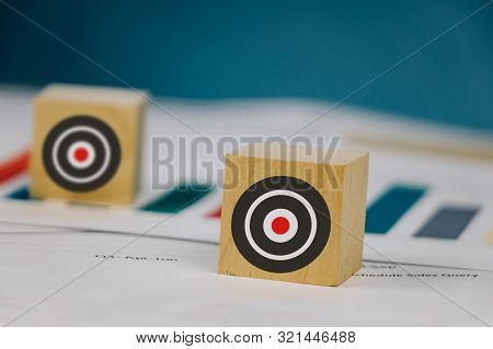 A Wooden Cubin Lies On A Table With Files With A Picture Of A Target.