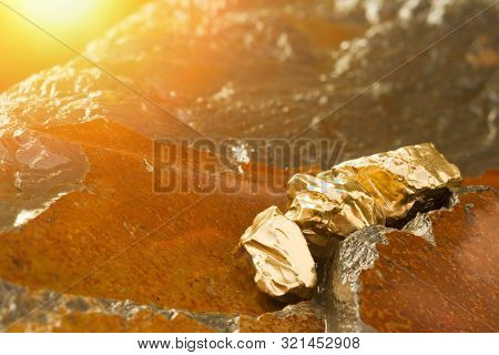 The Pure Gold Ore Found In The Mine On A Wet Stone By The River. Golden Bar In Nature With Shiny Sun