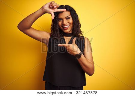 Transsexual transgender elegant businesswoman standing over isolated yellow background smiling making frame with hands and fingers with happy face. Creativity and photography concept.