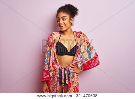 Young beautiful african american woman on vacation standing wearing bikini and colorful caftan