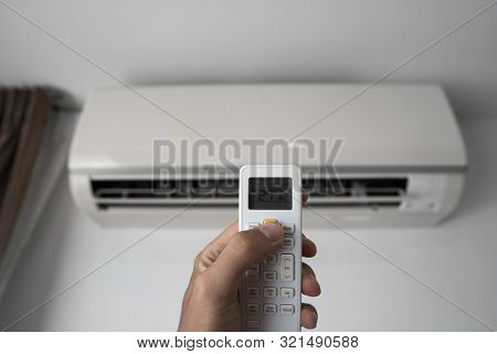 Mans Hand Using Remote Controler. Hand Holding Rc And Adjusting Temperature Of Air Conditioner Mount