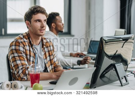 Thougtful Programmer Looking Up While Working Near African American Colleague
