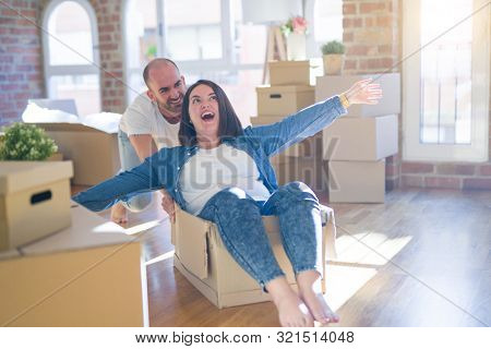 Funny and crazy couple having fun riding a cardboad box as a car, smiling happy and lauging at new home