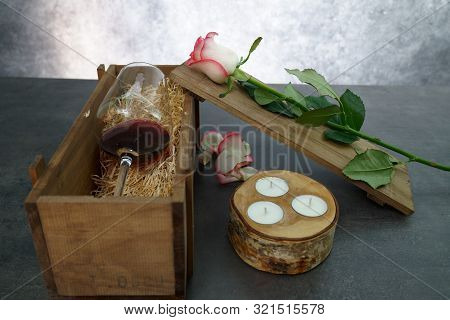 Red Wine Glass With Rose Flower On Concrete Table.