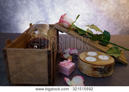Red Wine Glass With Rose Flower On Concrete Table.