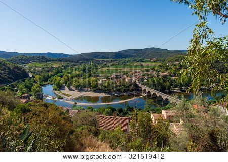 Landscape Of The Bend And Bridge On The River Orb Leading Into The Village Of  Roquebrun  In The Hau