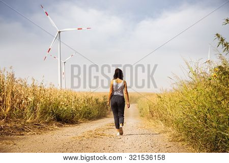 Woman In Countryside With Windmills. Lifestyle Concept. Hipster Woman Walking In Countryside With Wi