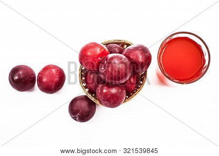Raw Organic Red Ripe Plums In A Brown-colored Basket Along With Its Extracted Tincture Or Extracted