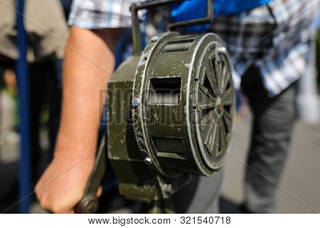 Shallow Depth Of Field Image With A Man Handling A Vintage Hand Crank Air Raid Siren