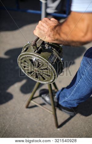 Shallow Depth Of Field Image With A Man Handling A Vintage Hand Crank Air Raid Siren