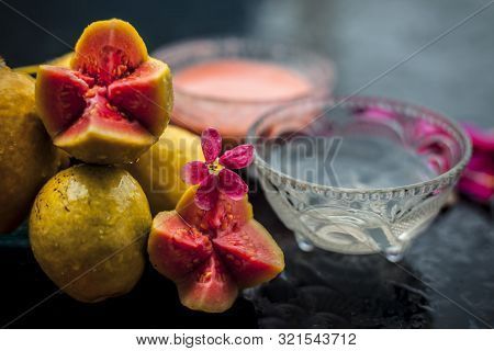Guava Pulp And Water Well Mixed In A Glass Bowl On The Wooden Surface Along With Some Raw Cut Guava,