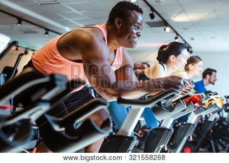 African man and friends exercising on fitness bike in gym