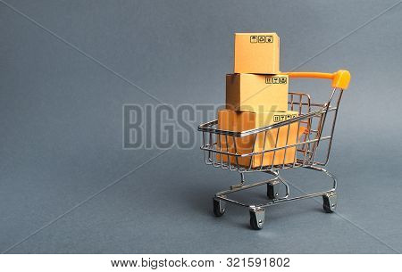 A Pile Of Cardboard Boxes In A Supermarket Trolley. Concept Of Shopping In The Online Store . E-comm
