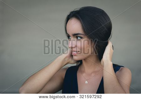 Closeup Portrait Of A Happy Young Brunette Teenage Girl Outdoor. Concrete Wall On Background