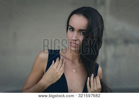 Closeup Portrait Of A Happy Young Brunette Teenage Girl Outdoor. Concrete Wall On Background