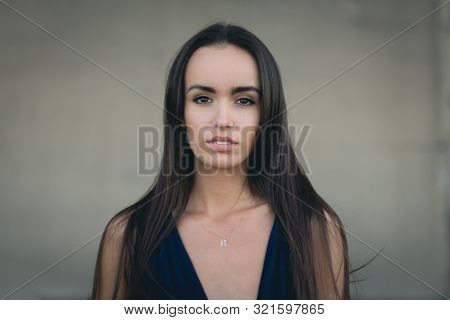 Closeup Portrait Of A Happy Young Brunette Teenage Girl Outdoor. Concrete Wall On Background