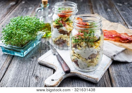 Brotzeit im Glas â traditional Bavarian snack with ham, eggs and black bread in a glass as closeup on a wooden board 