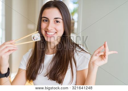 Beautiful young woman eating asian sushi using chopsticks very happy pointing with hand and finger to the side