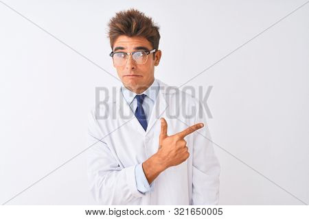 Young handsome sciencist man wearing glasses and coat over isolated white background Pointing aside worried and nervous with forefinger, concerned and surprised expression