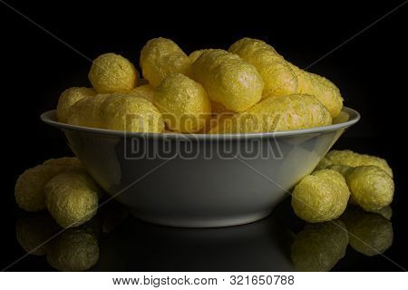 Lot Of Whole Salted Yellow Corn Puff In White Ceramic Bowl Isolated On Black Glass