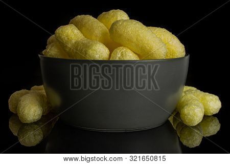 Lot Of Whole Salted Yellow Corn Puff In Gray Ceramic Bowl Isolated On Black Glass