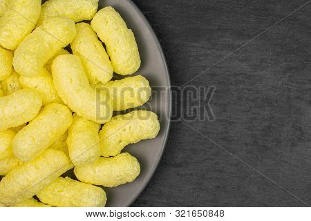 Lot Of Whole Salted Yellow Corn Puff On Gray Ceramic Plate Flatlay On Grey Stone
