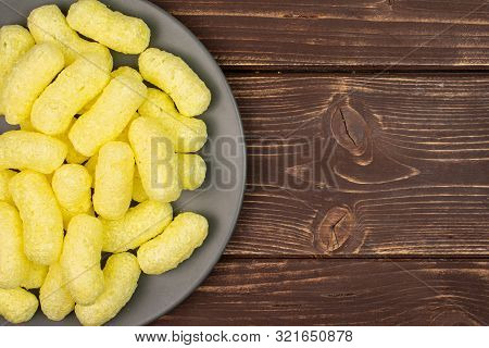 Lot Of Whole Salted Yellow Corn Puff On Gray Ceramic Plate Flatlay On Brown Wood