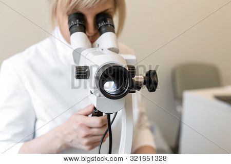 Young Female Professional Gynecologist In The Working Process, Looks Into The Colposcope.