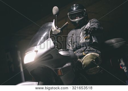 Biker On A Motorcycle Is Showing At Screen By His Index Finger.