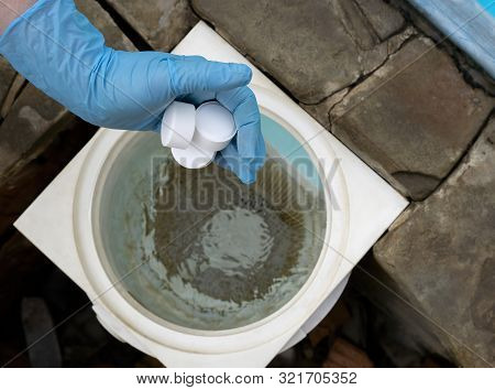 Female Hand Puts White Tablets Into Pool Skimmer. Cleaning, Disinfection Of Water In The Swimming Po