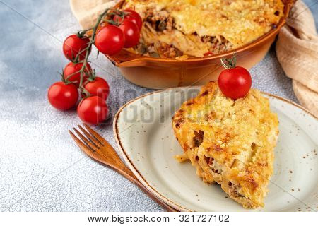 Golden Cannelloni With Meat, Tomatoes, Cheese Sauce And Pasta In Alternating Layers On A Rustic Plat