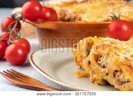 Golden Canelonni With Meat, Tomatoes, Cheese Sauce And Pasta In Alternating Layers On A Rustic Plate