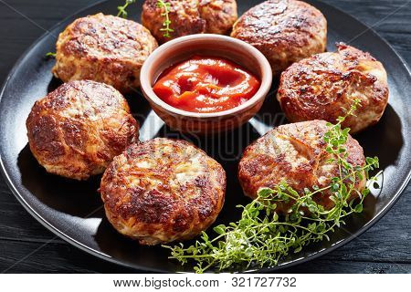 Cabbage Stew With Sliced Fried Sausages Served On A Plate On A Black Wooden Table, View From Above, 