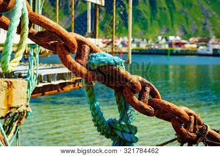 Rusty Old Metal Chain Links In Port. Marine Details. Bleik Village In The Background.