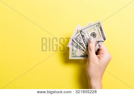 Female Hand Holding Tightly A Bundle Of Money. Top View Of Five And Fifty Dollars On Colorful Backgr