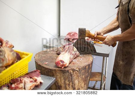 Butcher Chopping Meat With An Ax. Cut Beef Carcass In Position. The Process Of Cutting Veal