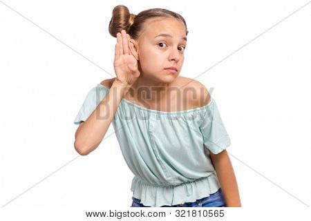 Portrait of teen girl holds her hand near her ear and listening something, isolated on white background. Cute caucasian young teenager overhears, listening an hearing to rumor or gossip.