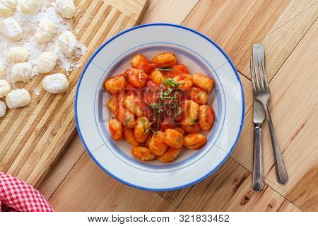 Italian Gnocchi In Red Marinara Tomato Sauce With Basil On Wooden Kitchen Table