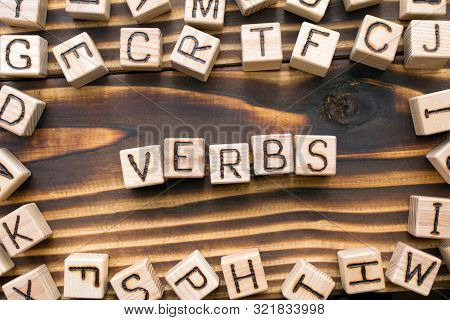 Word Verbs Composed Of Wooden Cubes With Letters, Part Of Speech Concept Scattered Around The Cubes 