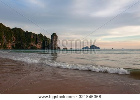 Picturesque beach with a view on the huge rock formation, sea view of Andaman sea and golden sand, iconic sight in Krabi province, Thailand.