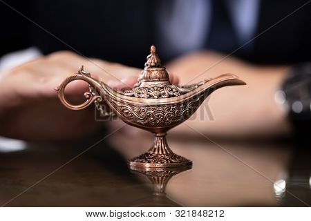 Businessman With Aladdin Ali Baba Lamp In His Hands Seeking Genie Help