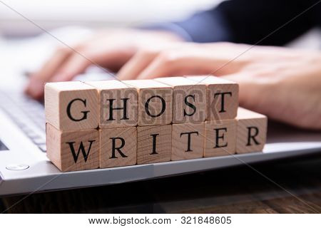 Ghostwriter Wooden Block On Computer Keyboard While Someone Typing