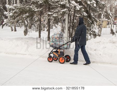 A Man In Warm Clothes, A Father Or Grandfather Walking In The Winter Park With A Baby Carriage, The 