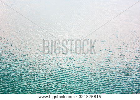 Texture Of Transparent Clear Surface Of Turquoise Azure Water With Small Ripples Fish And Sun Reflec