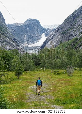 An Indefinite Man With T Goes To The Side Of A Glacier Through A Valley In Norway. One Of The Branch