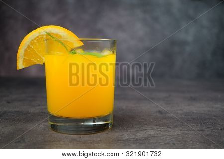 A Glass Of Fresh Orange Juice On Grey Background.