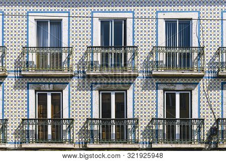 Typical Vintage Tile Facade Of A Portuguese Building With Windows, Balconies And Tiles With Geometri