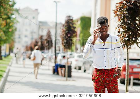 Portrait Of Handsome Stylish African American Model Man In Red Throusers And White Shirt With Cell P